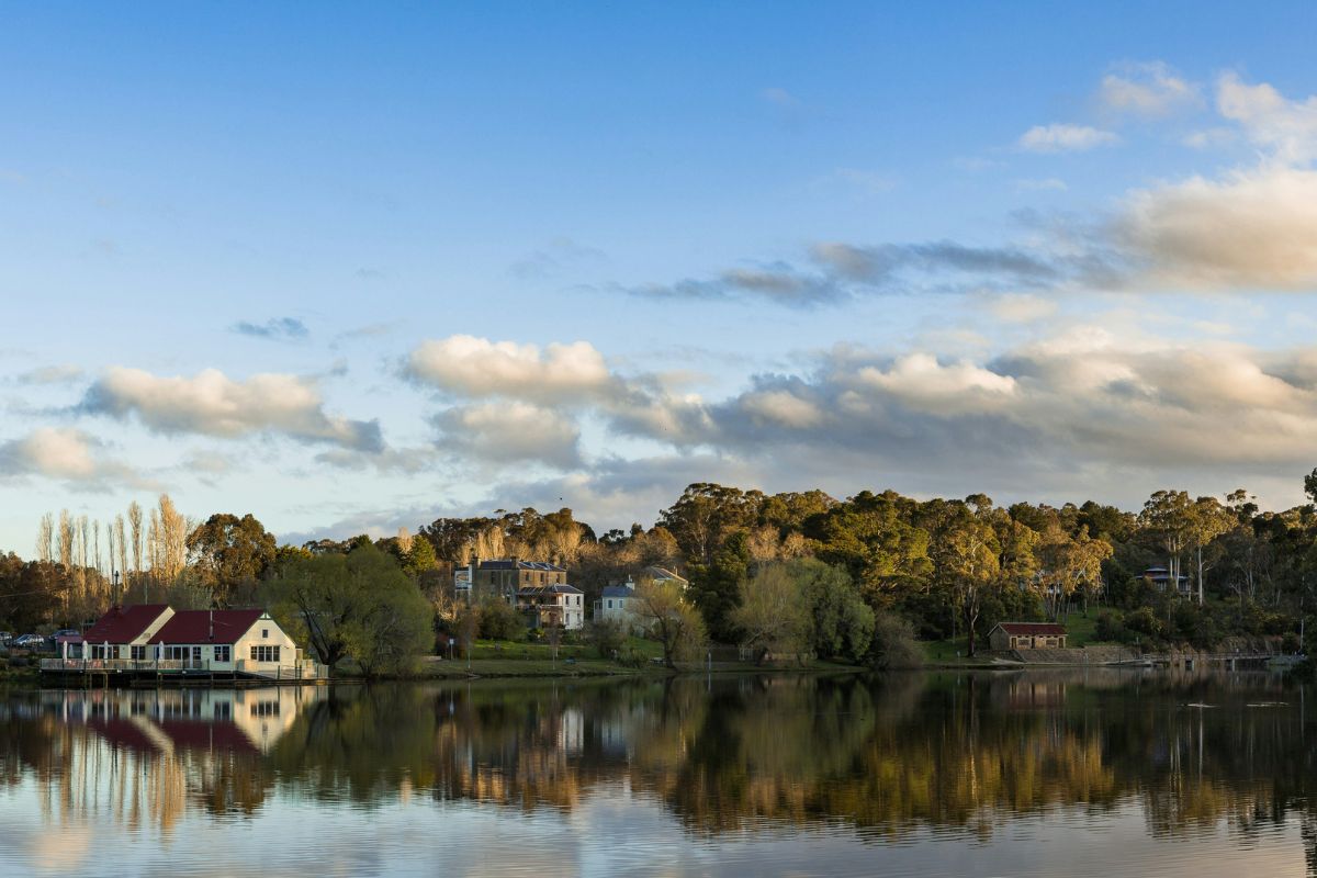Boathouse and old homes reflected in Lake Daylesford in late afternoon light